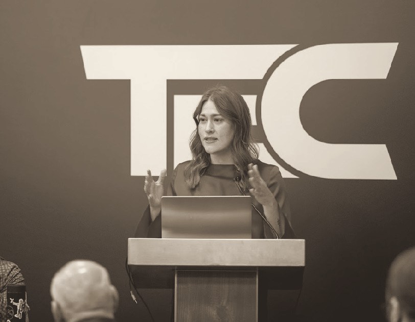 Brooke Erickson speaking from a podium, mid-gesture